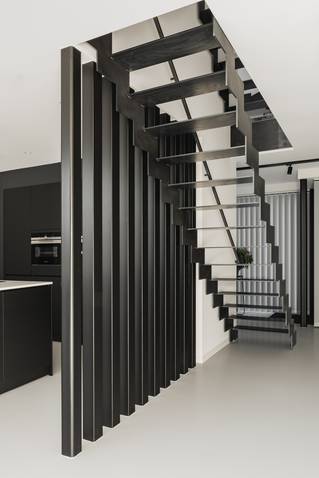 lichte Mellow PU gietvloer in zwarte keuken met metalen trap