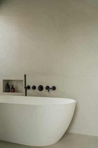 Vrijstaand bad met grijze Socrete gietvloer op wand