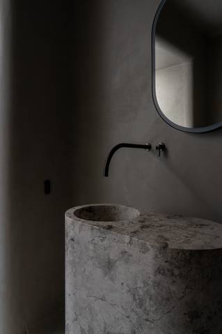 Natuursteen wastafel met grijze Socrete gietvloer op wand