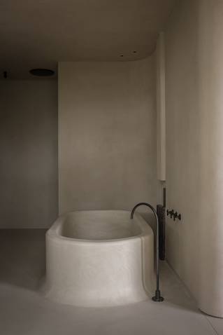 Minimalistische badkamer met grijze Socrete gietvloer dat doorloopt op bad