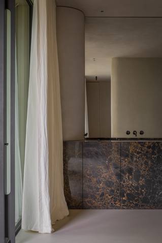 Badkamer met grijze Socrete gietvloer en wastafels in natuursteen