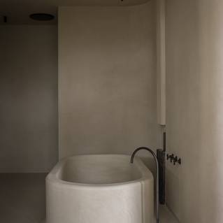 Minimalistische badkamer met grijze Socrete gietvloer dat doorloopt op bad