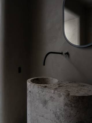 Badkamer met Socrete wand en natuursteen wastafel