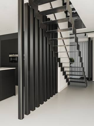 lichte Mellow PU gietvloer in zwarte keuken met metalen trap