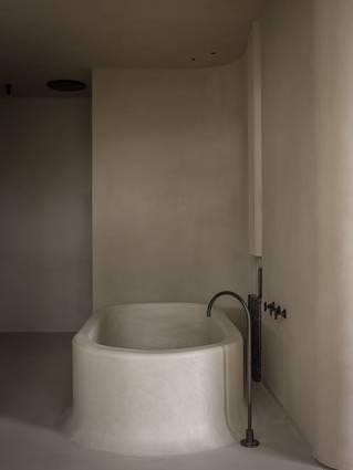 Minimalistische badkamer met grijze Socrete gietvloer dat doorloopt op bad