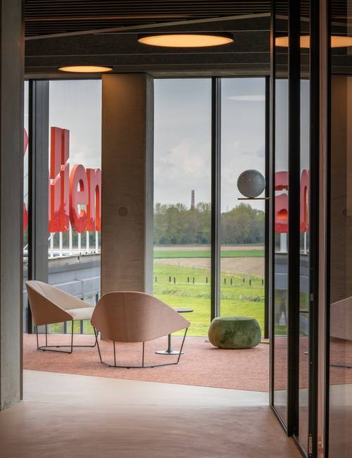 hal met zithoek op tapijt en socrete gietvloer